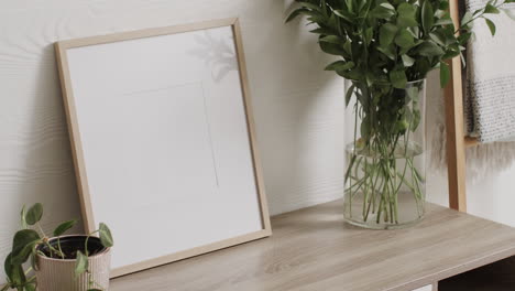 Wooden-frame-with-copy-space-on-white-background-with-plants-on-desk-against-white-wall