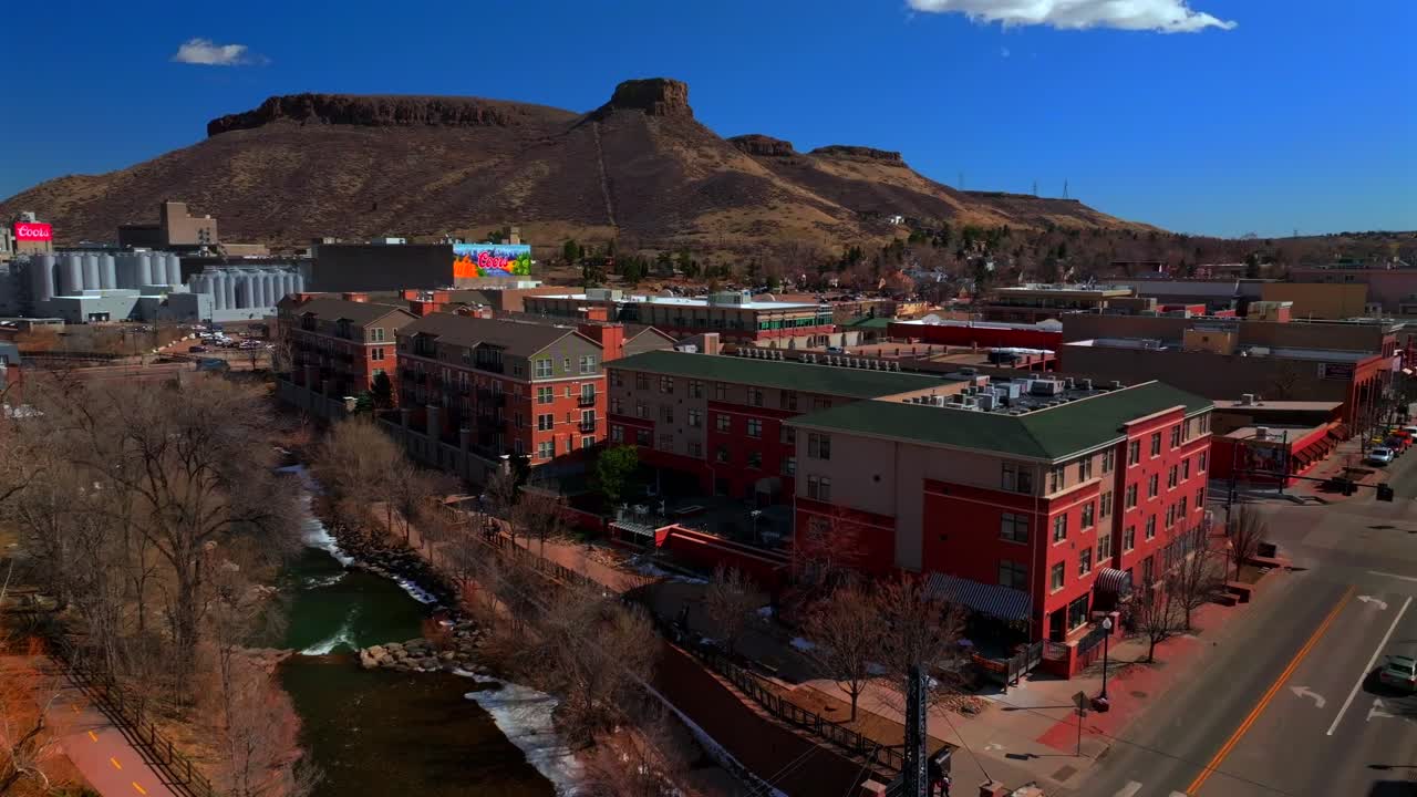 Historic downtown Golden Colorado aerial drone Clear Creek River North Table Mountain Coors Beer Factory Golden Gate Canyon winter sunny morning afternoon blue sky businesses buildings circle right