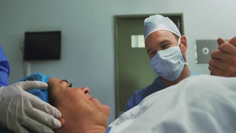 vista frontal de un hombre caucásico consolando a una mujer embarazada durante el parto en el teatro de operaciones en el hospital