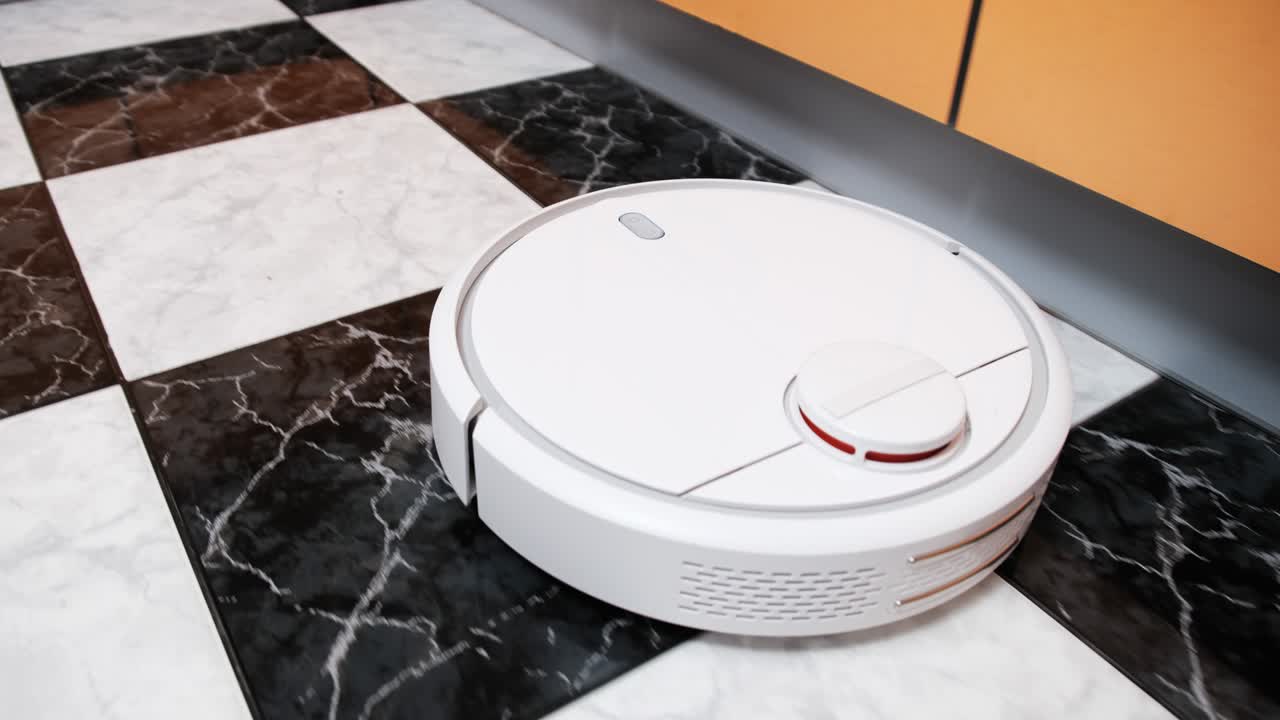 el aspirador robot limpia en la casa moderna en el piso de azulejos en la cocina