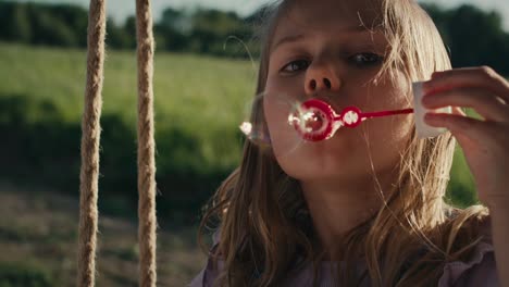 Close-up-of-caucasian-girl-playing-with-bubbles-and-swinging.