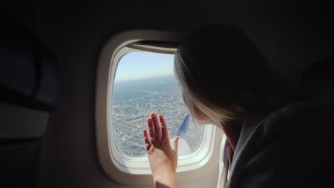 una pasajera mira por la ventana del avión al suelo debajo de donde se encuentra la gran metrópolis