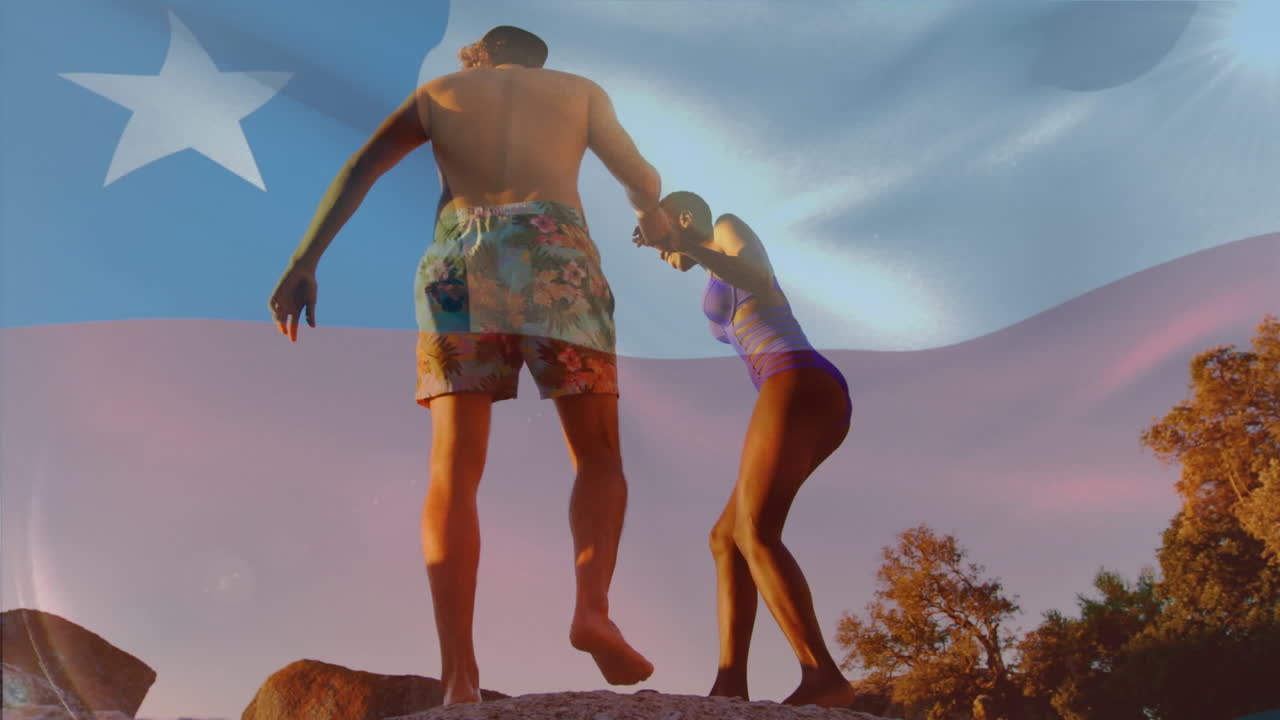 Animation of waving chile flag against biracial couple climbing rocks near the beach