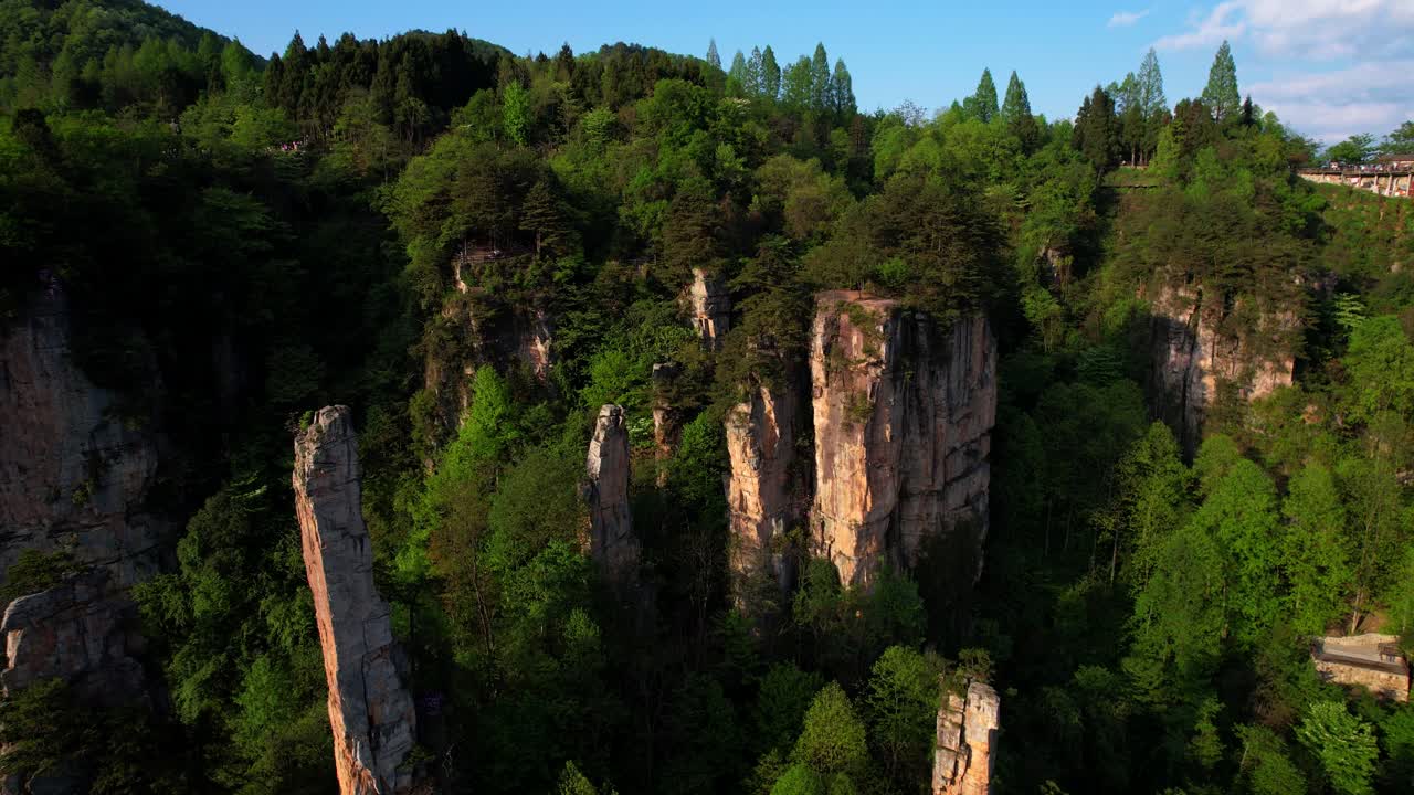 dron volando hacia una pareja en un punto de vista a través de altos pilares de piedra arenisca y exuberante vegetación en zhangjiajie, china