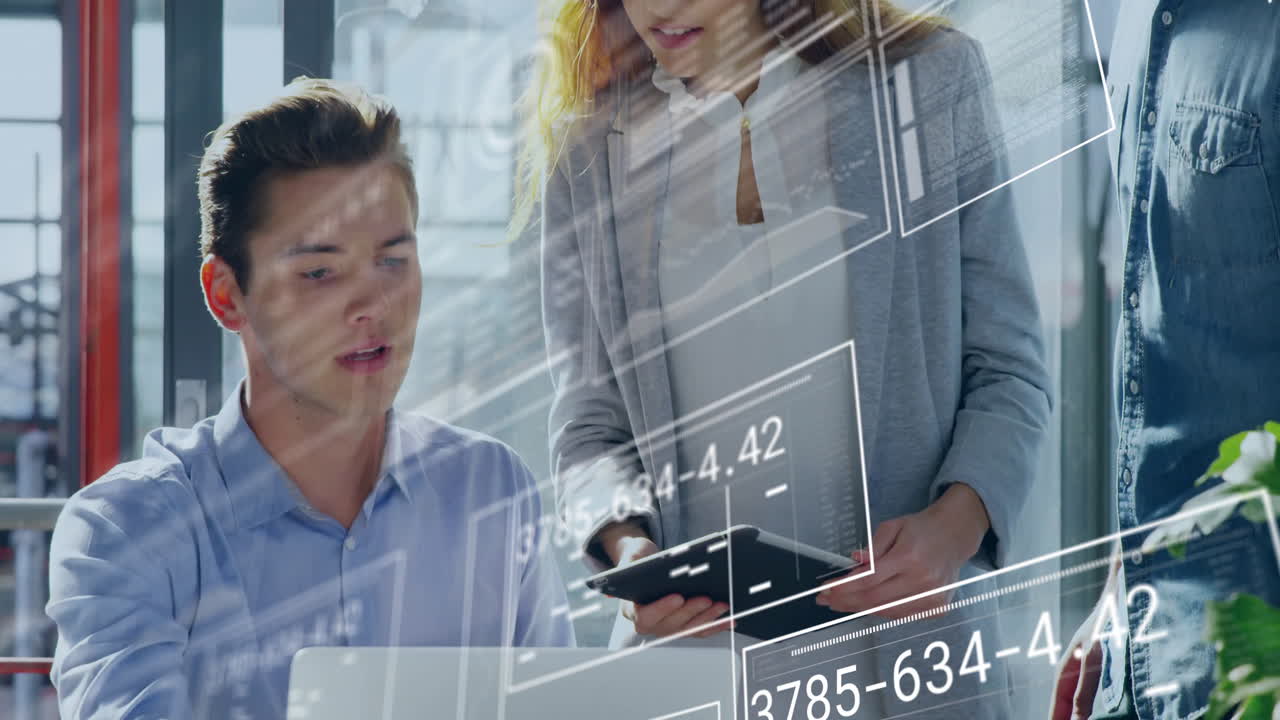 Three coworkers collaborating over laptops and tablets in corporate office, showing data overlays