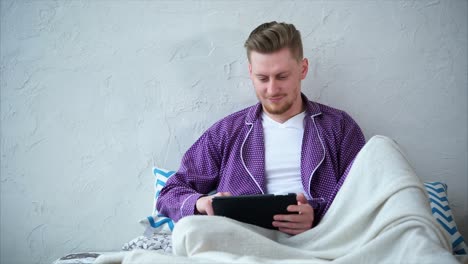 hombre usando tableta en la cama
