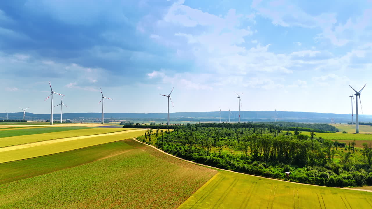 Windmills in the field produce green energy. Wind turbines work in the countryside at the backdrop of overcast sky