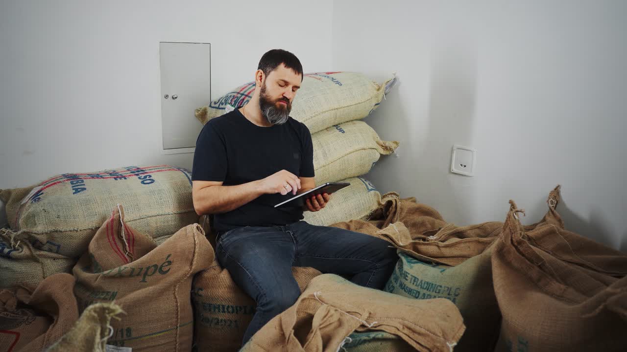 Man working with coffee bags and a tablet