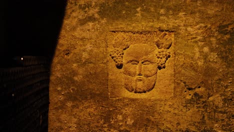 stone face carving in dimly lit catacombs