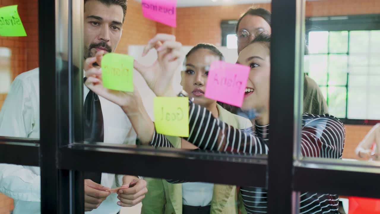 Diversity of young business people group have discussion meeting in office. Man, woman have communication brainstorming and put sticky note it on wall together. Corporate teamwork of modern colleague.