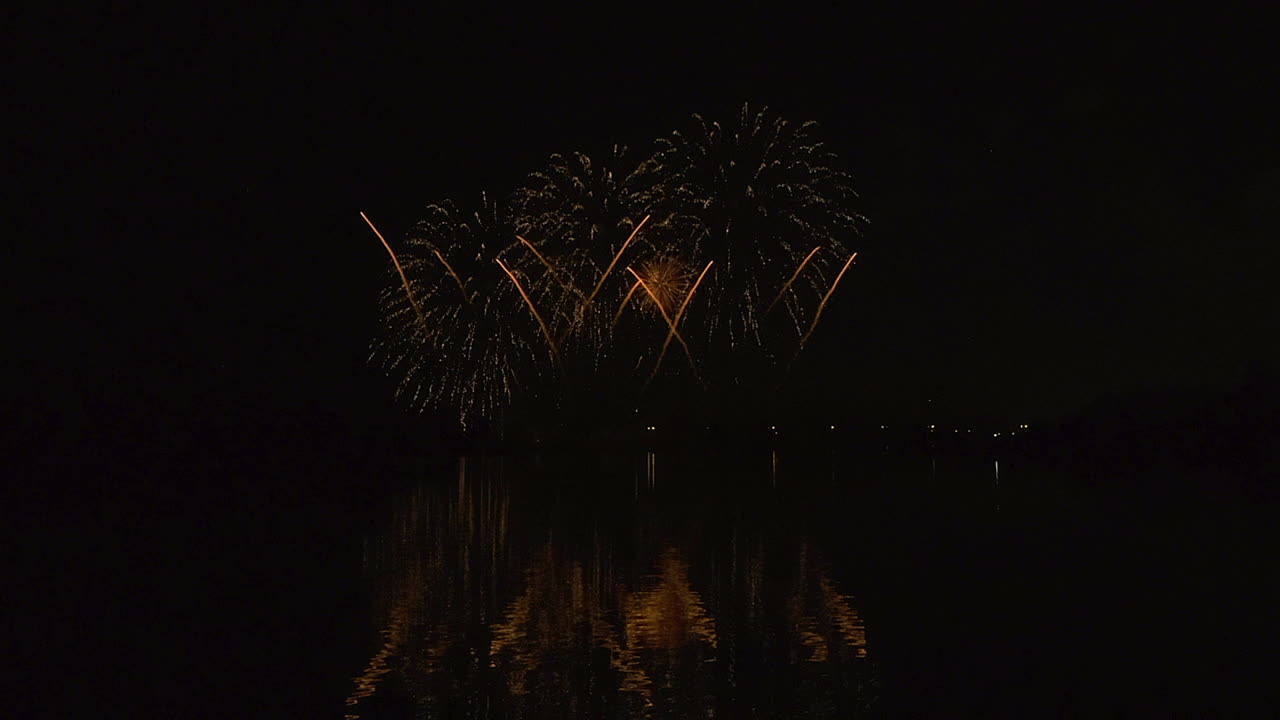 los fuegos artificiales de cometa y crisantemo estallan en simetría en el cielo nocturno oscuro