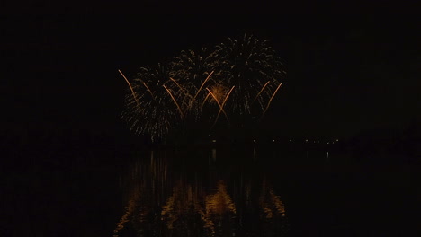 los fuegos artificiales de cometa y crisantemo estallan en simetría en el cielo nocturno oscuro