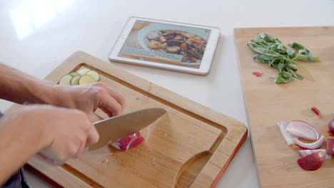 hombre sigue la receta en la tableta digital en la cocina filmado en r3d