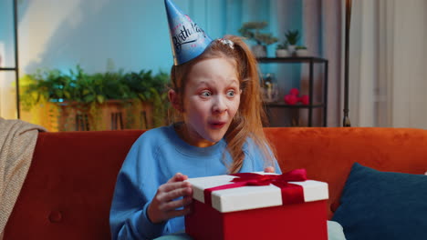 Niña-Feliz-Sostiene-Una-Caja-De-Regalo-De-Cumpleaños-Con-Cinta,-Celebrando-La-Fiesta,-Abriendo-El-Regalo-En-Casa