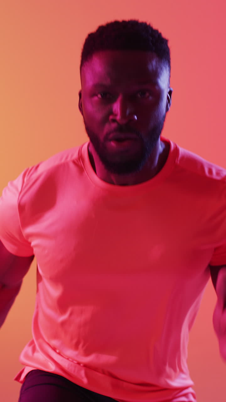 video vertical de un corredor afroamericano corriendo sobre un fondo naranja
