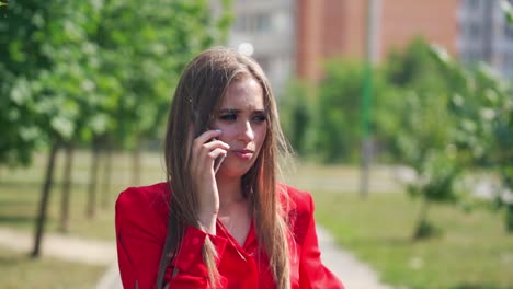 young woman talking on the phone. portrait of a beautiful lady with long hair holding a mobile phone on the blurred city background. slow motion.