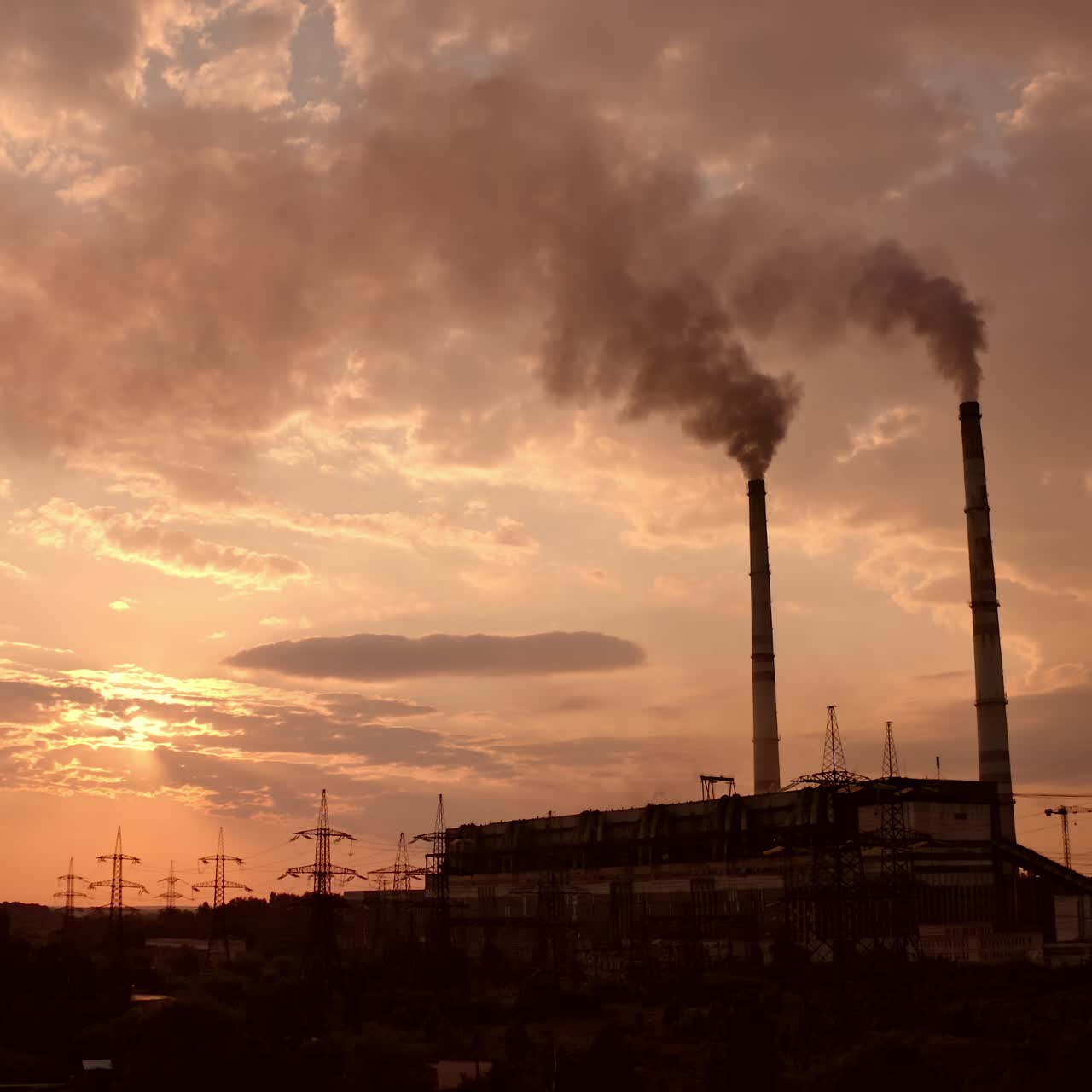 Harmful industrial area near the river. Power plant with smoking pipes pollute the atmosphere. Power station and factory at sunset. Industrial district. Smoke pipes against the evening sky