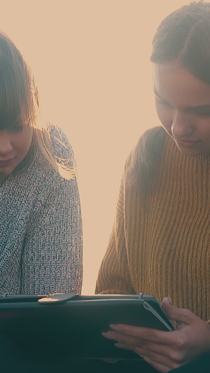 beautiful young women work on tablet and laptop near tent in bright morning sunlight close view slow motion
