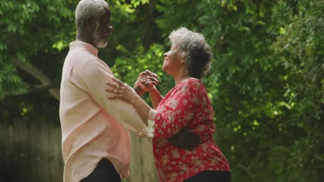 A-senior-African-american-couple-dancing-in-the-garden-in-social-distancing