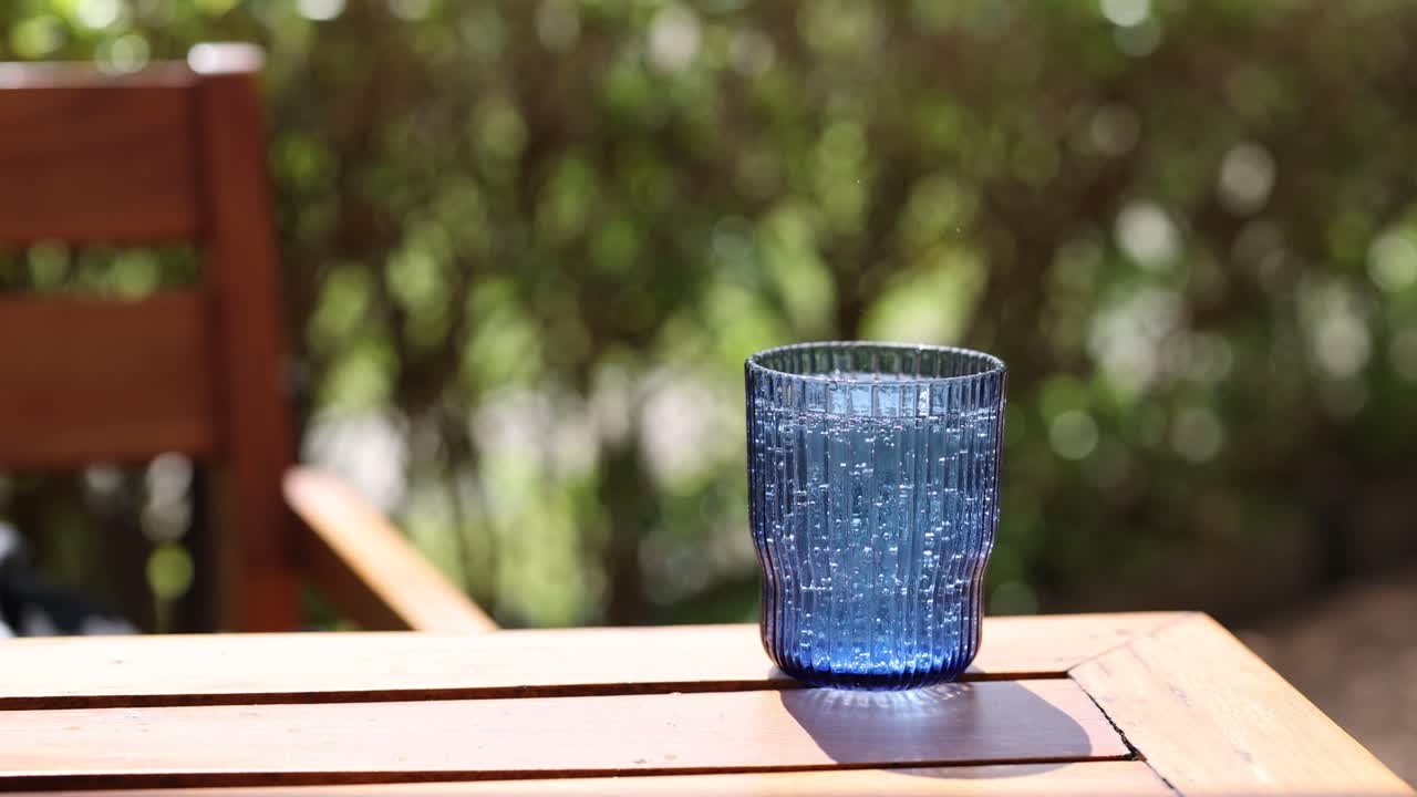 persona añadiendo una rebanada de limón a un vaso de agua gaseosa