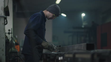 Un-Trabajador-De-Una-Fábrica-Trabaja-Con-Chispas-Metálicas-Voladoras-En-Cámara-Lenta.-Un-Hombre-Con-Gafas-Protectoras-Trabaja-Con-Pulido-De-Metales-Y-Desmontaje-De-Estructuras-Metálicas-De-Acero.