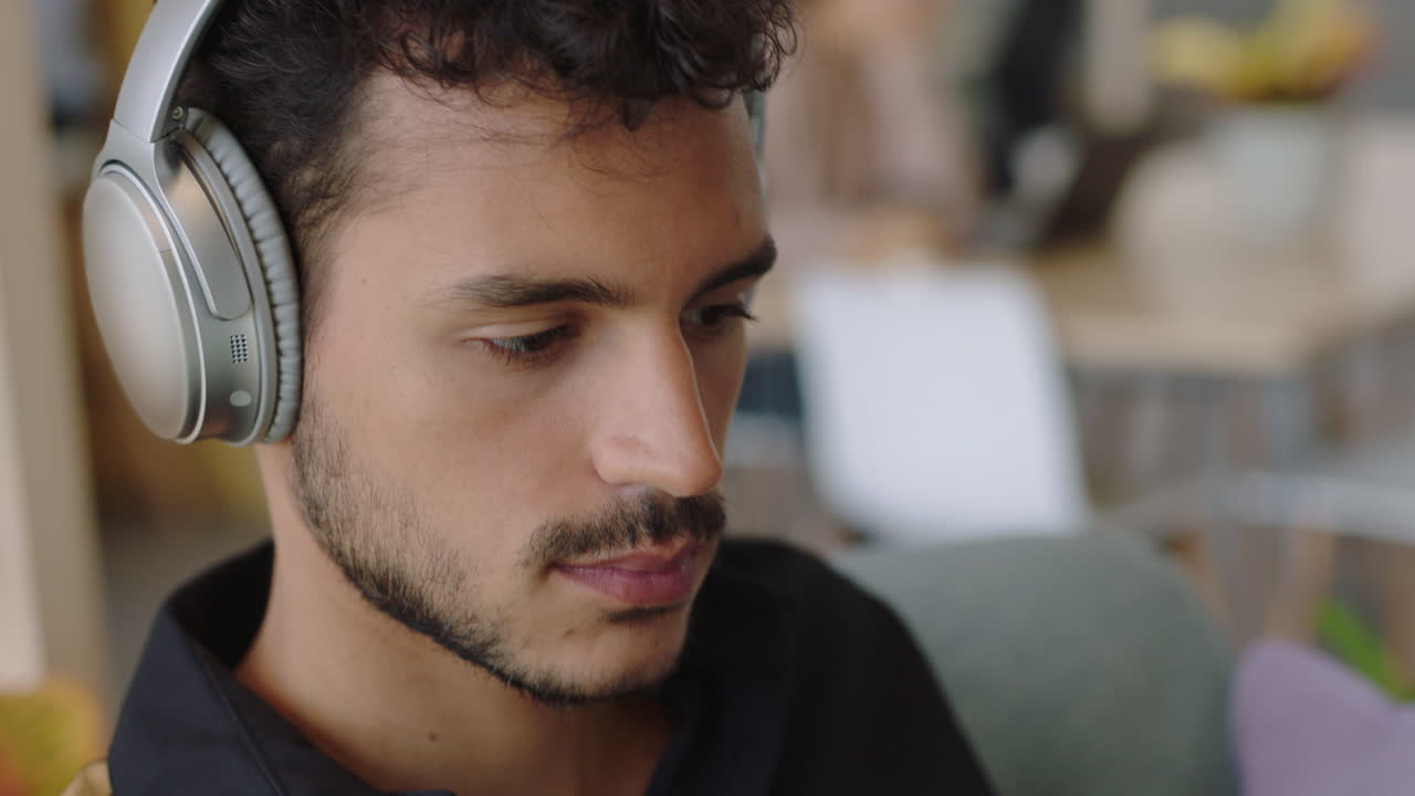 joven hispano que usa una computadora portátil navegando en línea compartiendo mensajes de comunicación de red estudiante que disfruta escuchando música revisando teléfonos inteligentes redes sociales en la oficina moderna