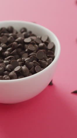 video de un cuenco de trozos de chocolate sobre un fondo rosado