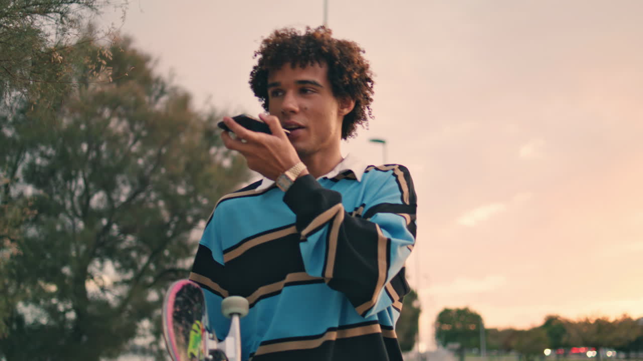 Millennial skater speaking cellphone sunset city closeup. Zoomer recording phone