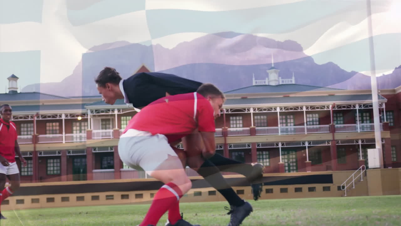 Tackling on field, rugby players with mountain and building in background