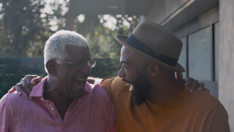 portrait of senior father talking and laughing with adult son in garden at home