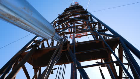 approaching really close to the tall metal tower used in drilling technology. low angle view on the support at the backdrop of blue sky.