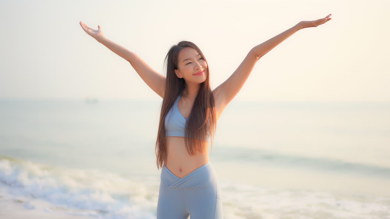 Happy asian fit girl embracing sunlight at beach