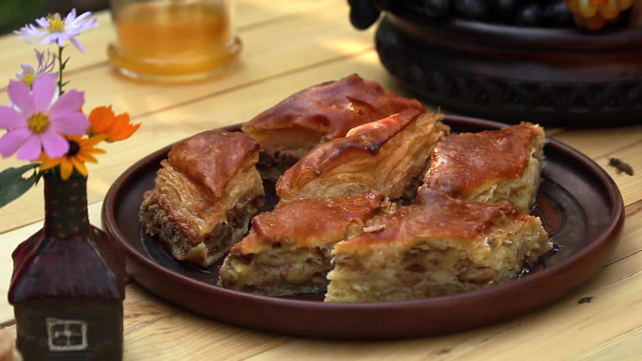 Masada, meyve kasesinin yanında taze yapılmış baklava dolu bir tabak.