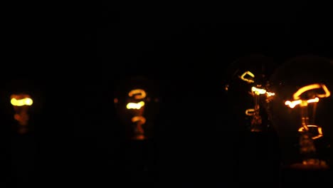 incandescent lamps with a red orange colored tungsten filament on a black background, slow pan shot