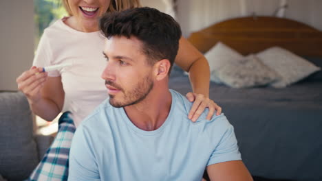 Close-Up-Of-Excited-Couple-In-Bedroom-At-Home-Celebrating-Positive-Pregnancy-Test-Result