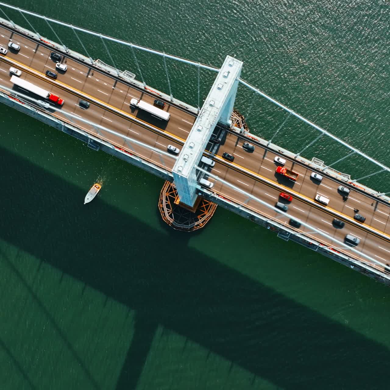 Flight above the beautiful bridge with six-lane road on. Yacht sailing under the bridge. Top view