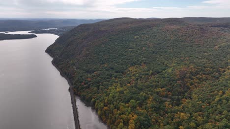 an aerial view high over the mountains in upstate ny during the fall foliage change, on a beautiful day with white clouds