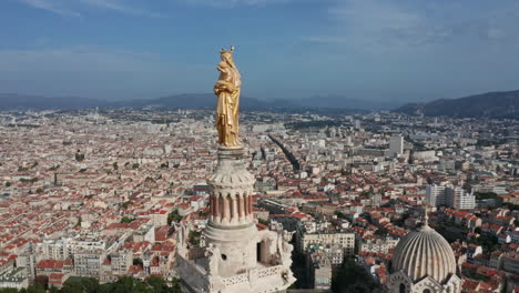 Primer-Plano-Aéreo-De-La-Estatua-En-La-Parte-Superior-De-La-Basílica-De-Notre-Dame-De-La-Garde-En-Marsella-Francia