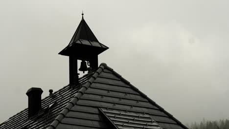 small bell hanging on house roof under cloudy sky