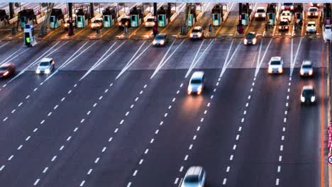 static timelapse of cars driving through highway toll booth at dusk