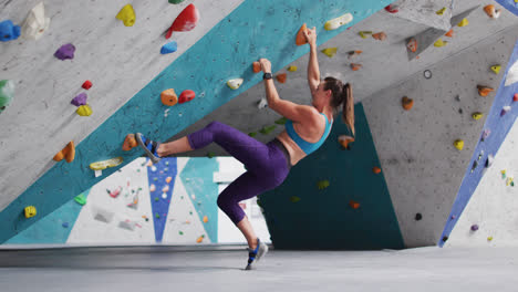 caucasian woman wearing face mask climbing wall at indoor climbing wall