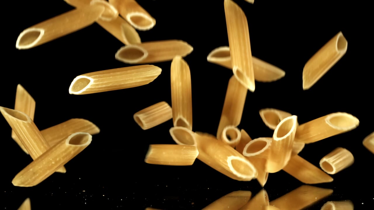 Pasta penne che cade al rallentatore su sfondo nero