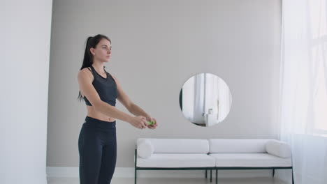 brunette woman does warm-up and exercises in her apartment in the morning turns the body blindly and right with arms straightened.