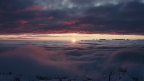 Toma-Aérea-épica-De-Un-Dron-Que-Muestra-La-Puesta-De-Sol-Sobre-El-Paisaje-Nublado-Y-Las-Montañas