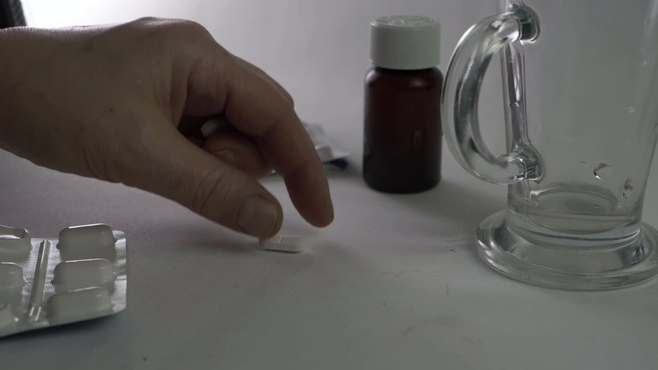 물 한 잔으로 두통 정제를 손에 들고 총을 닫습니다.