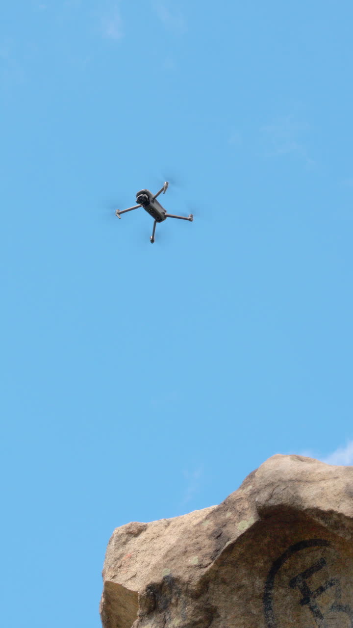 Small Drone Flying and Hovering in a Clear Blue Sky