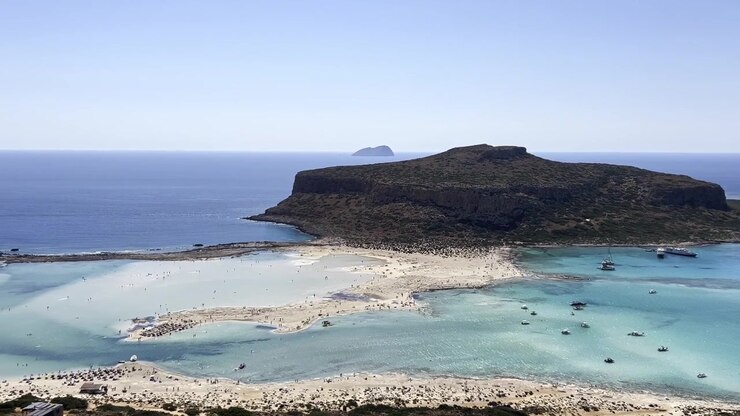 Vista panorâmica em câmera lenta da deslumbrante lagoa de Balos, mostrando águas rasas turquesa, bancos de areia brancos e barcos ancorados em Creta, Grécia