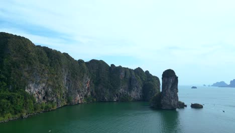 Breathtaking-view-of-a-secluded-bay-with-turquoise-water,-surrounded-by-towering-cliffs-covered-in-lush-green-vegetation