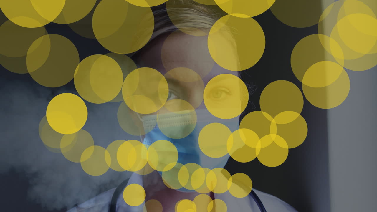 얼굴 마스크를 입은 백인 여성 의사 위에 노란 점의 애니메이션