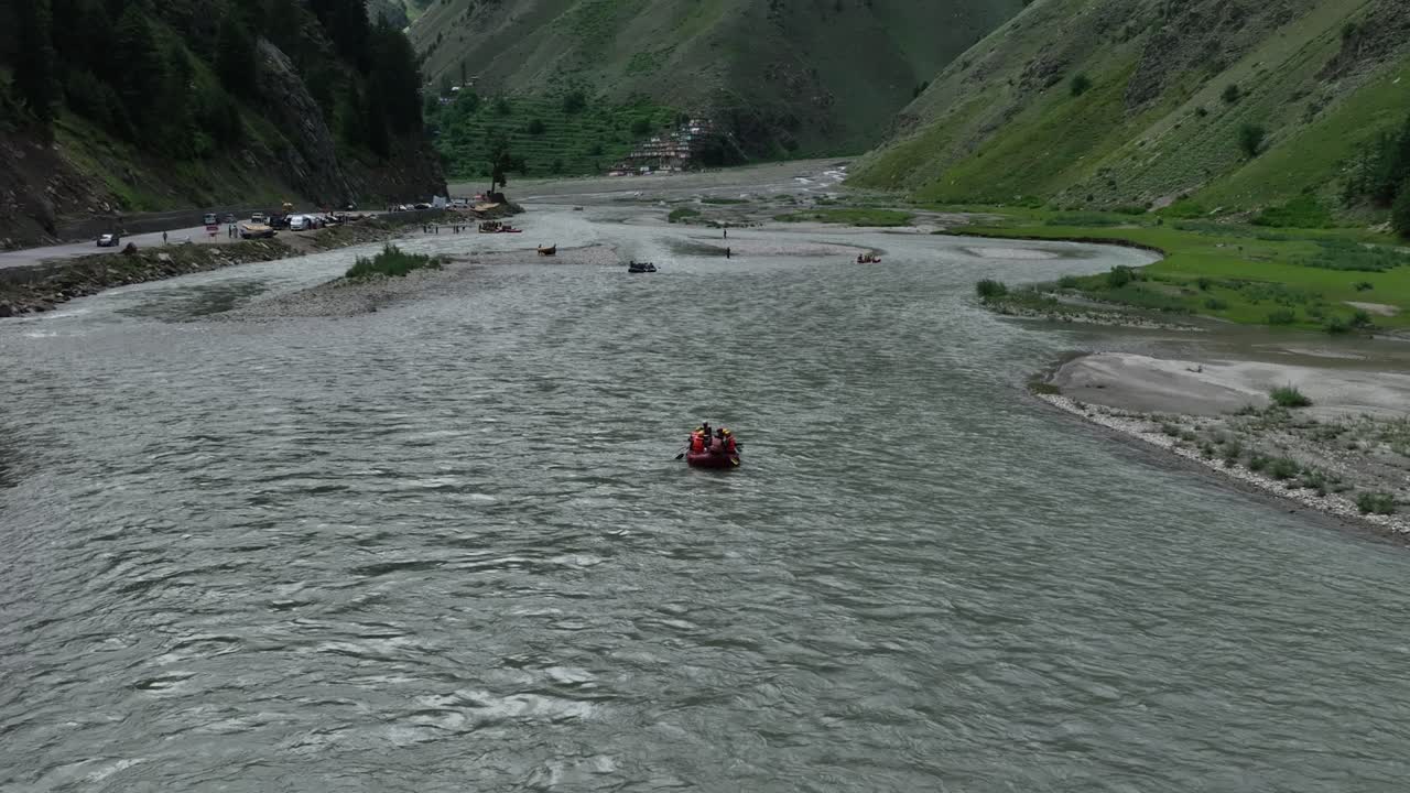 Il drone sorvola i rafters che navigano le vivaci acque blu di Naran, con l'inquadratura che si allarga gradualmente per rivelare lo scenario mozzafiato di montagne imponenti
